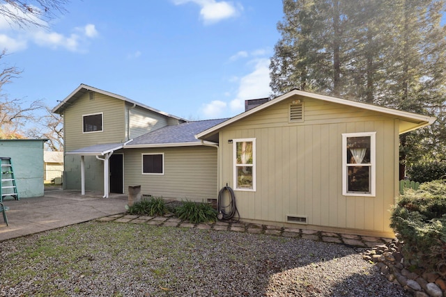 back of property featuring crawl space, roof with shingles, a chimney, and a patio area