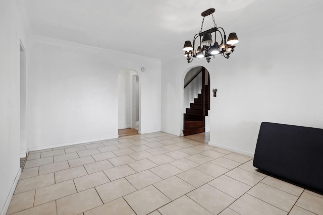 empty room featuring baseboards, light tile patterned flooring, arched walkways, stairs, and a chandelier