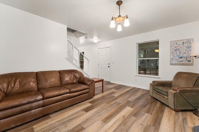 living area with a chandelier, wood finished floors, stairs, and baseboards