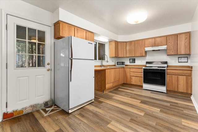 kitchen featuring range with electric stovetop, freestanding refrigerator, a sink, wood finished floors, and under cabinet range hood