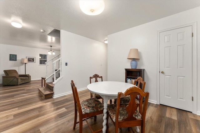 dining area featuring a textured ceiling, stairway, wood finished floors, and baseboards