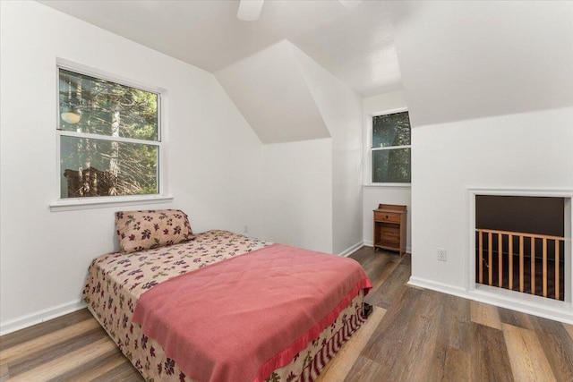 bedroom with vaulted ceiling, wood finished floors, and baseboards