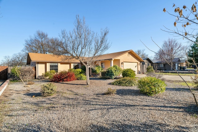 ranch-style home with a garage, fence, and stucco siding