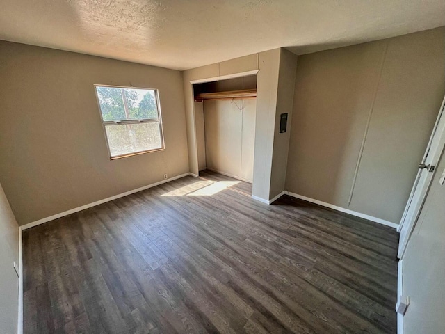 unfurnished bedroom featuring dark wood-style floors, a closet, a textured ceiling, and baseboards