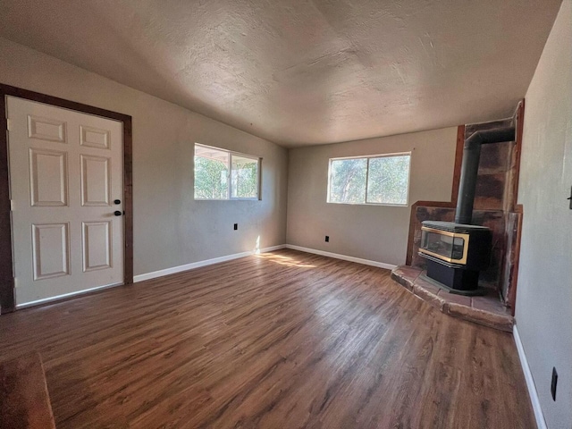 unfurnished living room with baseboards, dark wood-style flooring, and a healthy amount of sunlight