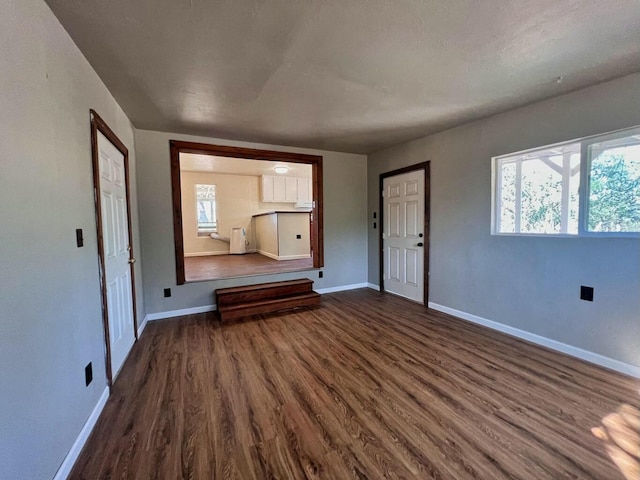 spare room featuring a wealth of natural light, dark wood finished floors, and baseboards