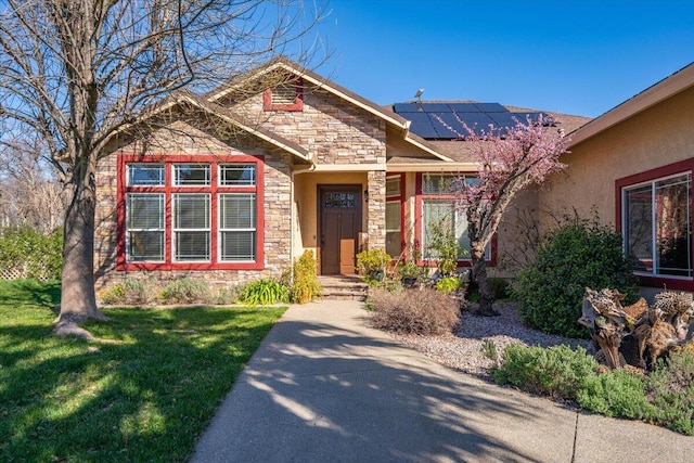 craftsman house featuring stone siding, a front lawn, solar panels, and stucco siding