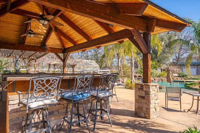 view of patio / terrace featuring outdoor dry bar, a gazebo, ceiling fan, and an outdoor pool