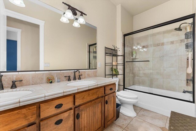 full bath with toilet, tile patterned flooring, double vanity, and a sink