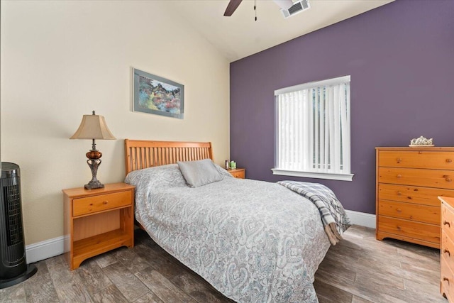 bedroom with lofted ceiling, visible vents, baseboards, and wood finished floors