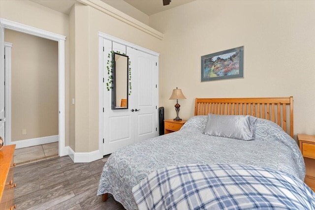 bedroom featuring ceiling fan, baseboards, a closet, and wood finished floors