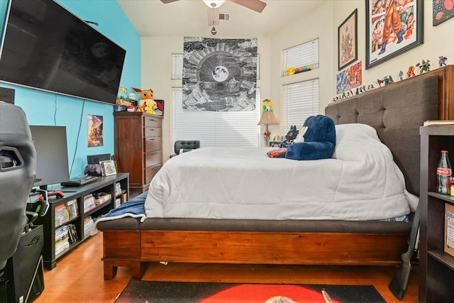 bedroom featuring a ceiling fan, visible vents, and wood finished floors