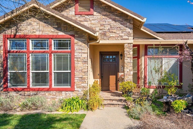 view of front of house featuring stone siding and solar panels