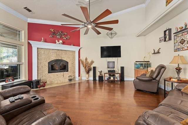 living area featuring a fireplace, wood finished floors, visible vents, a ceiling fan, and ornamental molding