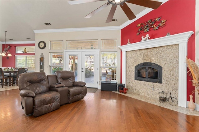 living area with french doors, ornamental molding, a fireplace, and wood finished floors