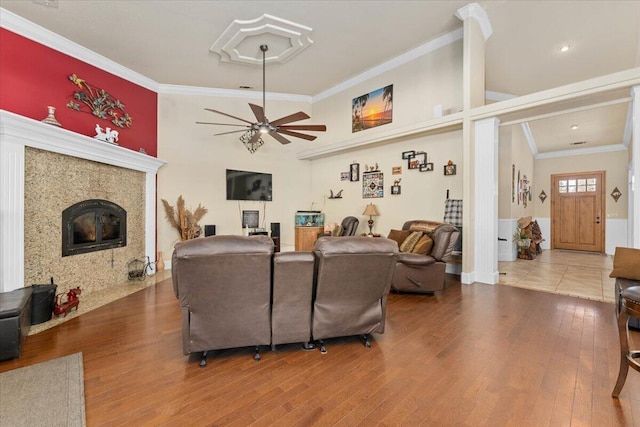 living area featuring ceiling fan, a tiled fireplace, wood finished floors, and crown molding