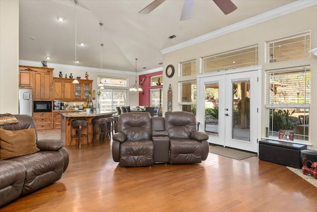 living area featuring high vaulted ceiling, light wood-style flooring, visible vents, and french doors