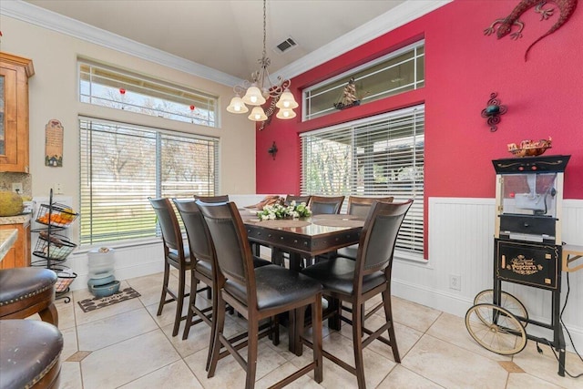 dining space featuring a wainscoted wall, ornamental molding, light tile patterned floors, and visible vents