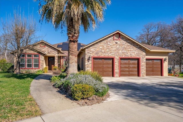 ranch-style house with a garage, concrete driveway, stone siding, roof mounted solar panels, and a front lawn