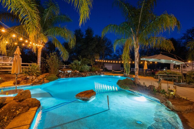 pool at twilight featuring fence, an outdoor pool, and a patio