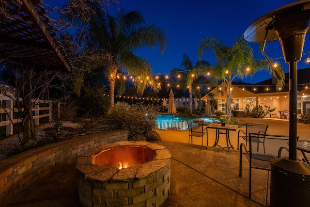 patio at twilight featuring a fire pit and an outdoor pool