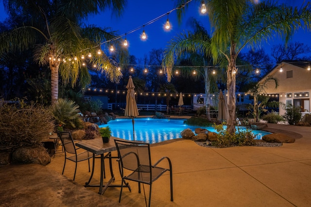 pool at twilight featuring a patio area and an outdoor pool