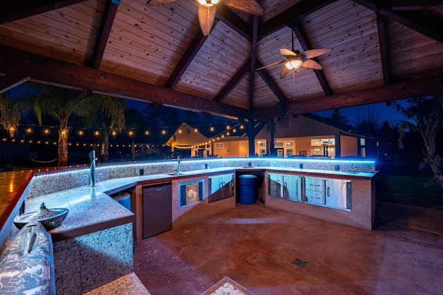 patio at twilight with ceiling fan, visible vents, an outdoor kitchen, and a sink