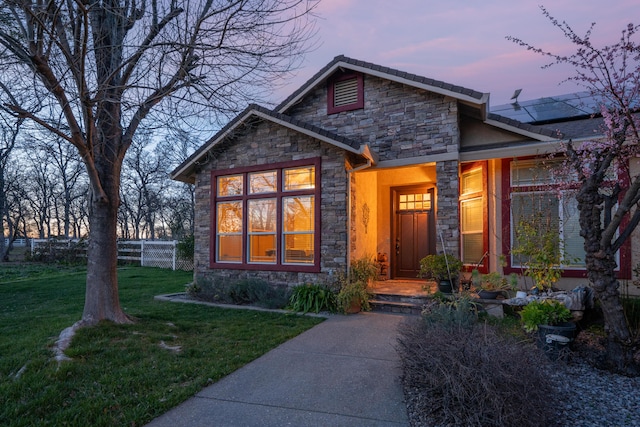 view of front facade featuring stone siding, a yard, and fence