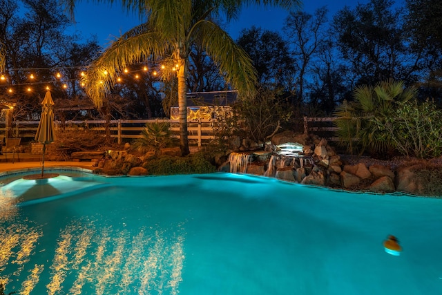 pool at twilight featuring fence and an outdoor pool