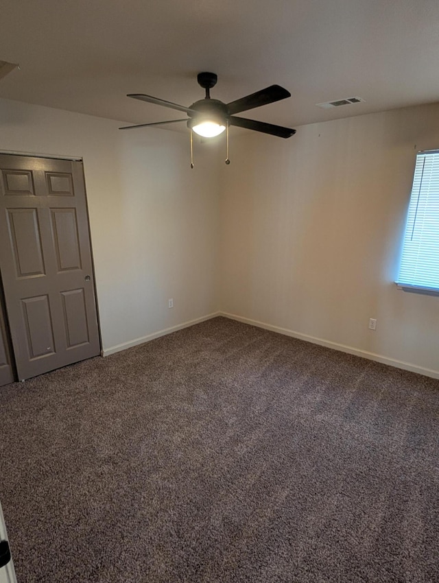 carpeted empty room featuring baseboards, visible vents, and a ceiling fan