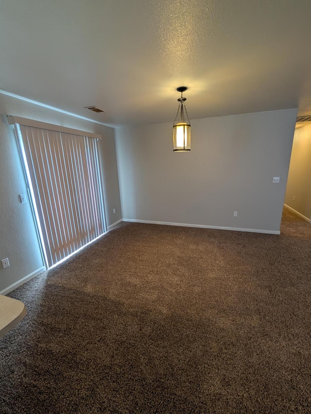 empty room featuring a textured ceiling, carpet flooring, visible vents, and baseboards