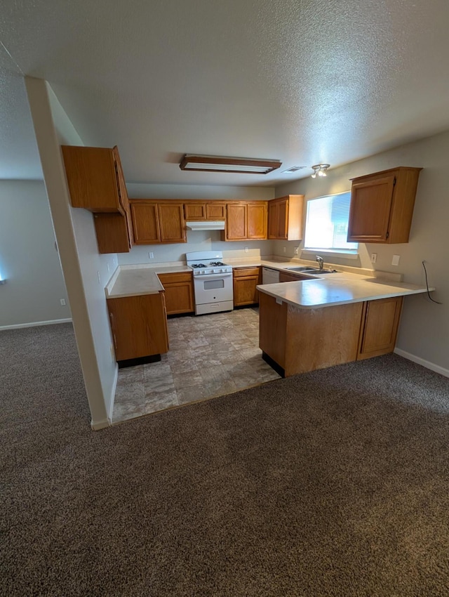 kitchen featuring white gas range, light colored carpet, a sink, a peninsula, and under cabinet range hood