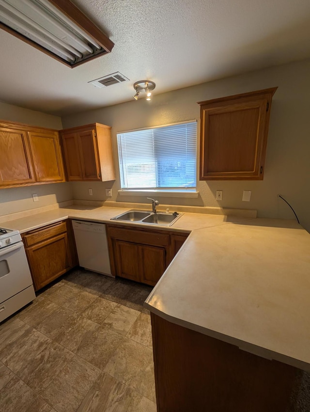 kitchen featuring white appliances, visible vents, brown cabinetry, light countertops, and a sink