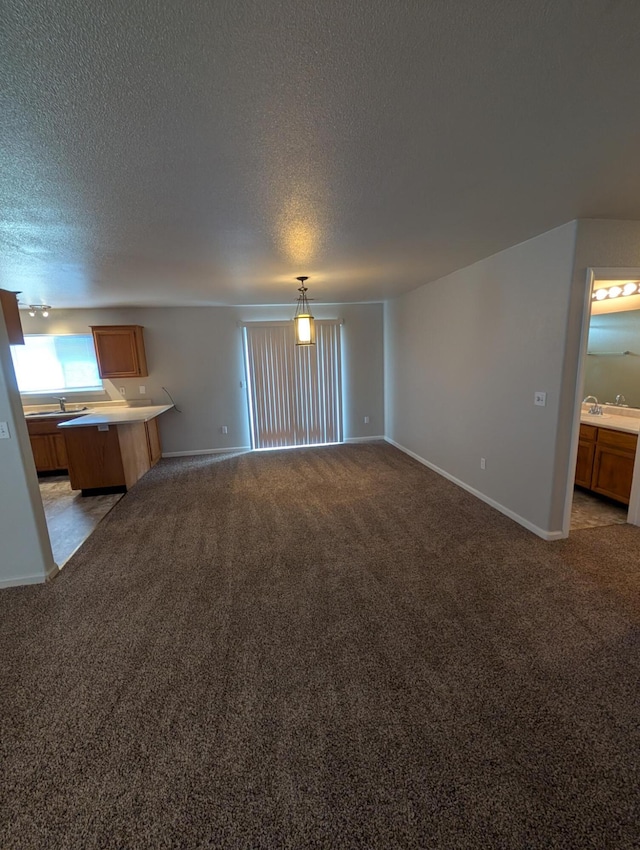 unfurnished living room featuring light carpet, a sink, baseboards, and a textured ceiling