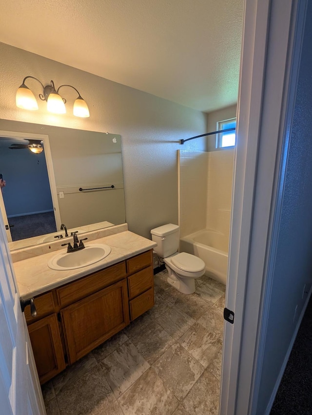 bathroom featuring a textured wall, toilet, vanity, a textured ceiling, and shower / bathtub combination