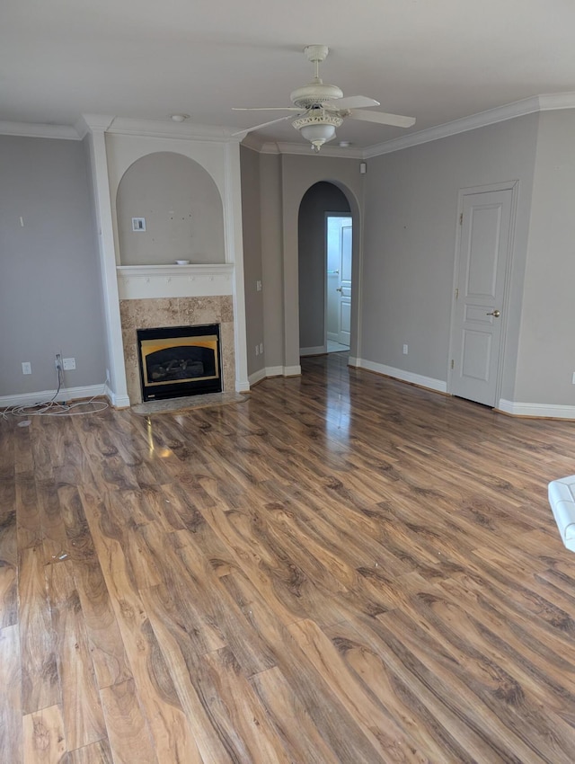 unfurnished living room featuring a fireplace, baseboards, crown molding, and wood finished floors