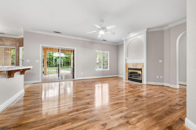 unfurnished living room featuring visible vents, a fireplace, ornamental molding, a ceiling fan, and light wood-style floors