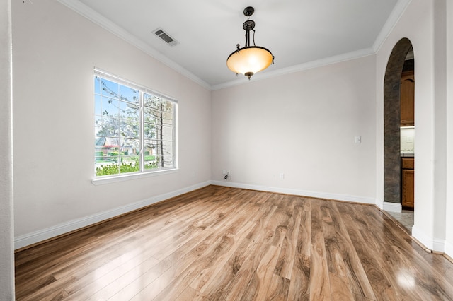 spare room with arched walkways, ornamental molding, visible vents, and light wood finished floors