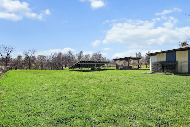 view of yard featuring a pole building, an outdoor structure, and fence