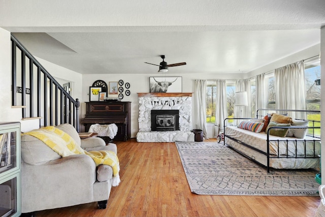 living area with a ceiling fan, a fireplace, stairway, and wood finished floors