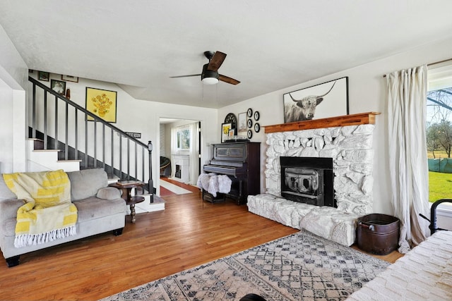 living area featuring stairway, a fireplace, wood finished floors, and a ceiling fan