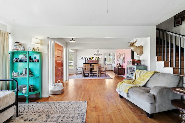 living area with a notable chandelier, stairs, and wood finished floors