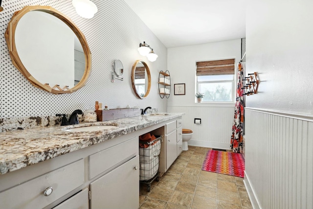 full bathroom featuring a wainscoted wall, a sink, and toilet