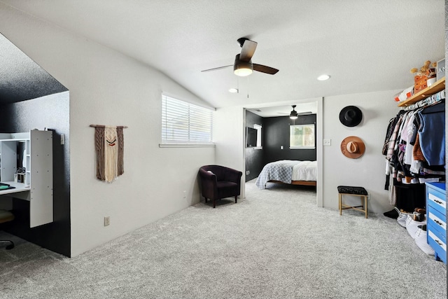 carpeted bedroom with ceiling fan, vaulted ceiling, and a textured ceiling