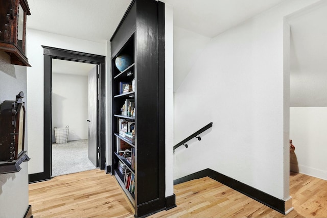 corridor featuring an upstairs landing, light wood-style flooring, and baseboards