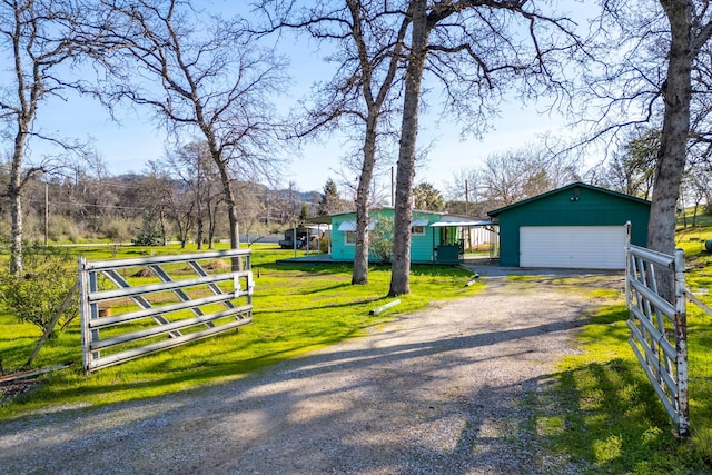 view of front of house with an outbuilding, a detached garage, a front lawn, and driveway