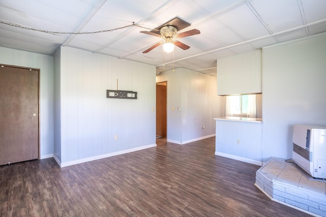 unfurnished living room with a ceiling fan, heating unit, wood finished floors, and baseboards