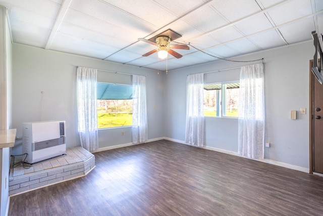 unfurnished room with baseboards, heating unit, wood finished floors, and a ceiling fan