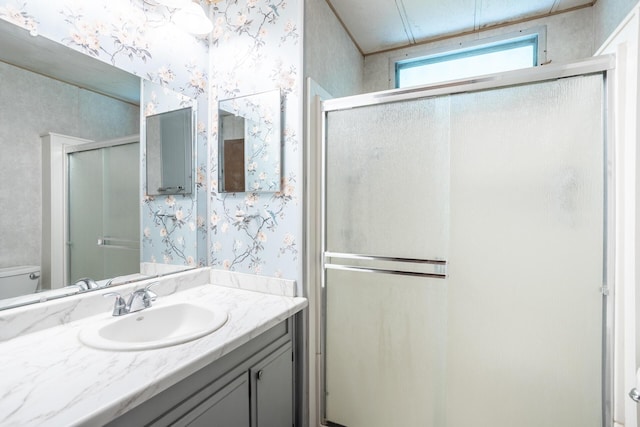 bathroom featuring toilet, a stall shower, wallpapered walls, and vanity