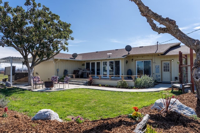 rear view of property featuring a lawn, a deck, and a patio area